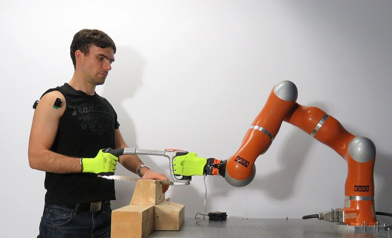 Researcher working beside a robot during controlled collaborative sawing experiments