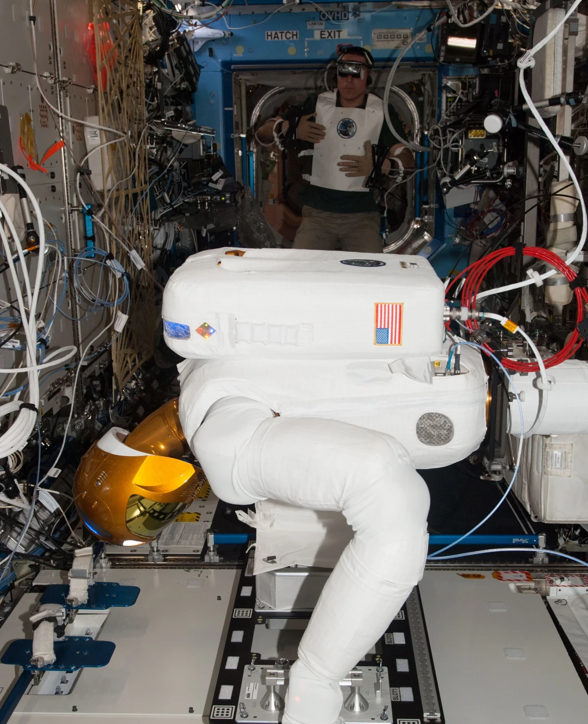 NASA宇宙飛行士がロボノート2号をテレオペレーションするためにベスト、手袋、バイザーを着用している