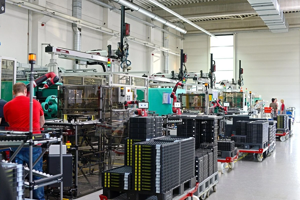 Collaborative robot arms operating beside production equipment and workers