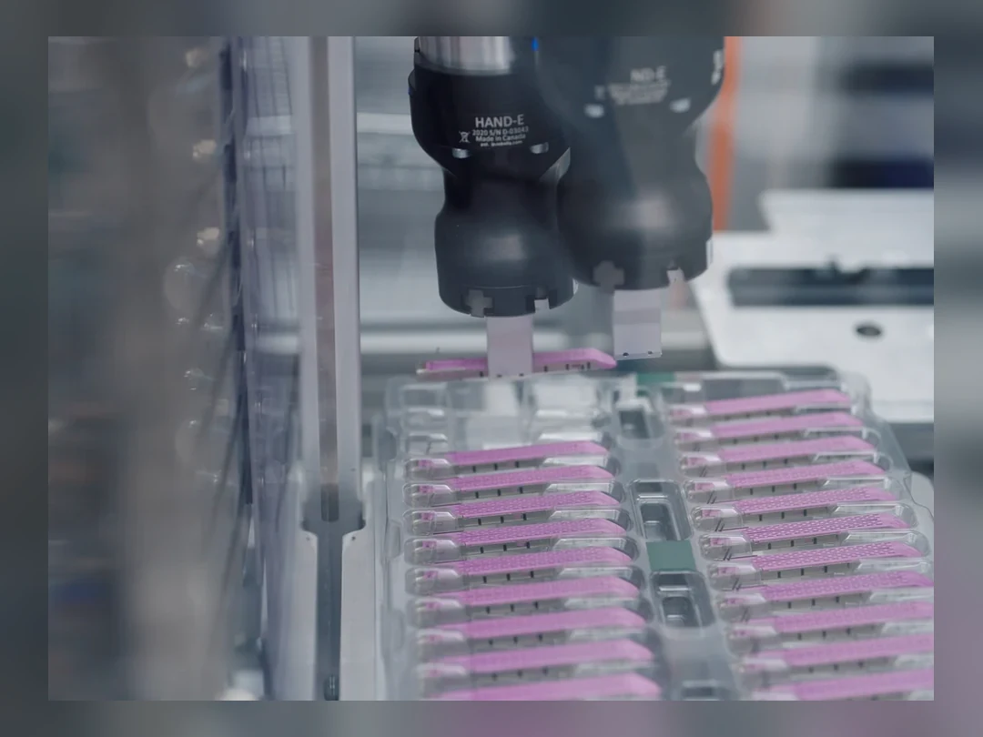 Manufacturing robot gripper handling component trays on a production line