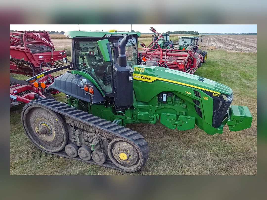 야외 농지에 세워진 녹색 John Deere 궤도형 트랙터