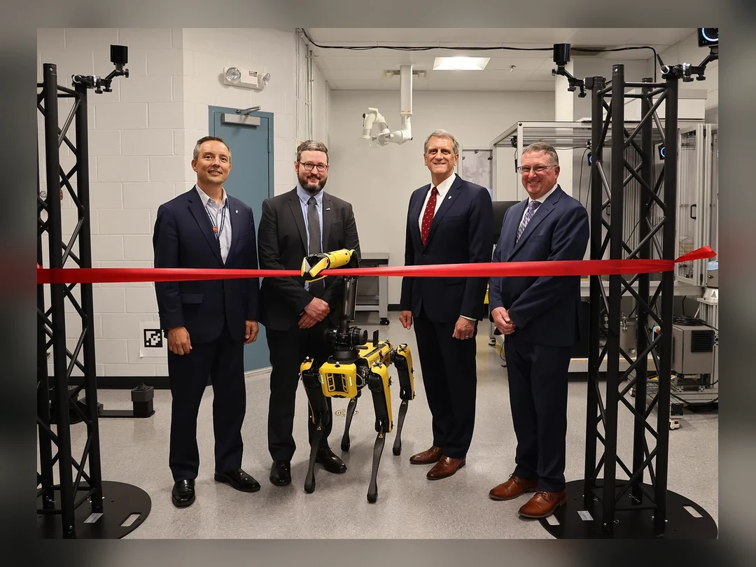 Officials standing with a quadruped robot in a U.S. Air Force automation lab